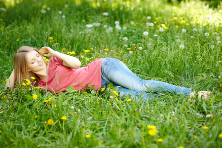 Spring girl lying on the field of dandelions in full lengthの写真素材
