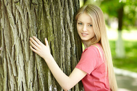 Pretty young female hugging a tree, looking at cameraの写真素材