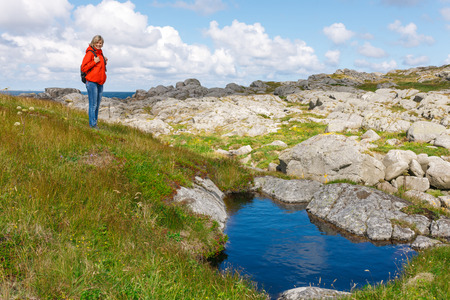 Remote view of happy woman hiker standing on wild nature of Norwayの写真素材