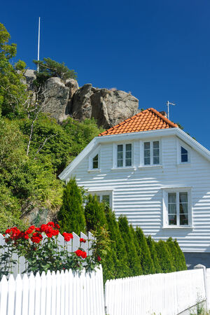 Traditional white wooden house in Norway attached to a mountain, summer dayの写真素材