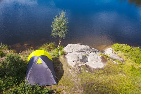 Camping in the wilderness. Camping tent on a shore of mountains lakeの写真素材