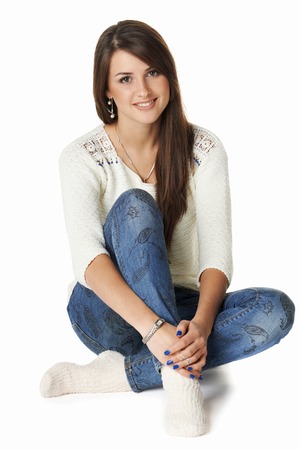 Smiling yong woman sitting on floor, studio isolated on whiteの写真素材