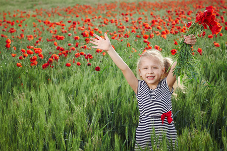 Little girl on the poppy meadow greeting happy with hands outspreadの写真素材