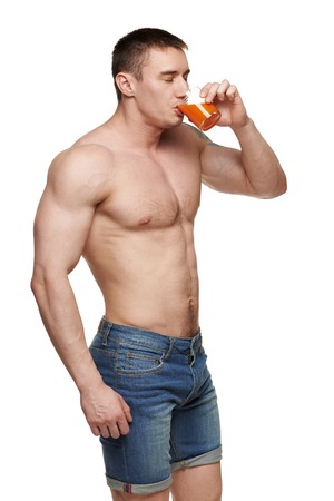 Muscular shirtless male drinking juice, isolated on white backgroundの写真素材