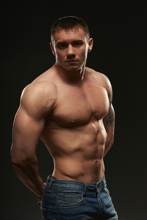 Muscular man posing in studio over black backgroundの写真素材