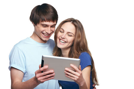 Closeup of young couple laughing while websurfing on internet, against white の写真素材