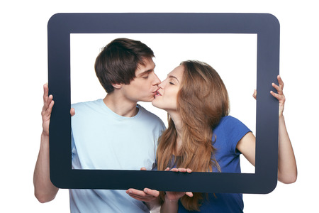 Happy in love couple holding tablet frame and kissingの写真素材