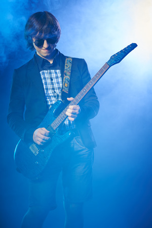 Young guitarist performing on stage, smoky scenicの写真素材