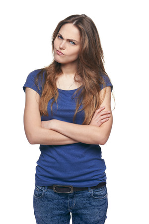 Young discontent girl with folded hands scowling, over white backgroundの写真素材