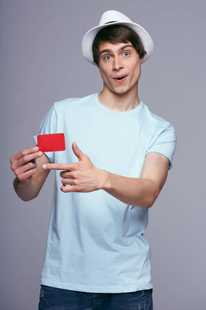 Surprised casual man showing blank credit card, on gray backgroundの写真素材