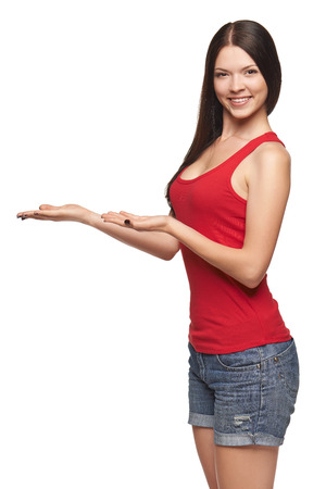 Smiling young woman in bright red top showing open hand palm with copy space for product or textの写真素材