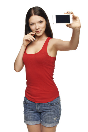 Happy young girl taking pictures of herself through cell phone, over white backgroundの写真素材