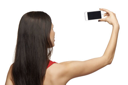 Back view of young woman taking pictures through cell phone, over white backgroundの写真素材