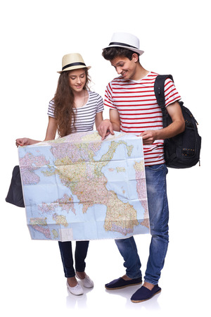 Full length of young couple with travel suitcases looking a destination on the map, over white backgroundの写真素材