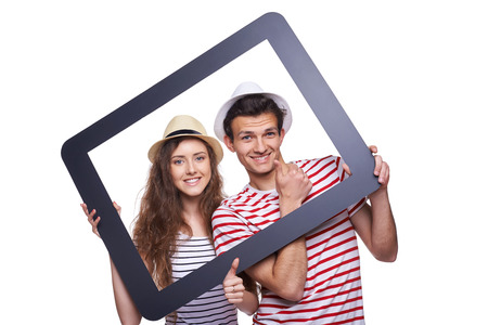 Happy couple looking through tablet frame and giving thumb upの写真素材