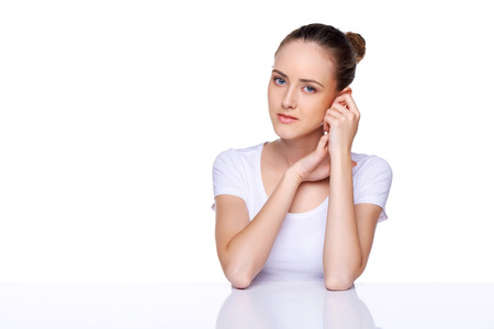 Beauty girl portrait  Young natural woman with clean face sitting at white table leaning on her elbows, over white backgroundの写真素材
