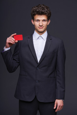 Fashionable smiling business man showing blank credit card, over gray background の写真素材
