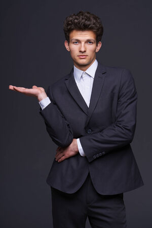 Businessman showing something, fashionable man showing open hand palm with copy space for product or textの写真素材