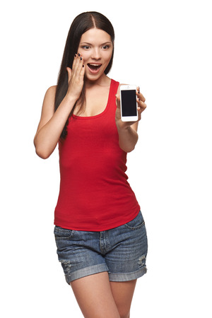 Excited surprised woman showing cell phone with black screen over white backgroundの写真素材