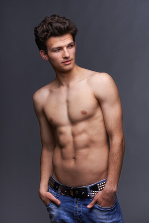 Male fashion model with modern haircut posing shirtless over dark の写真素材