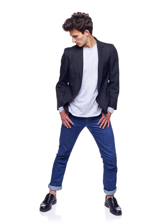 Full body of a fashion man with modern haircut posing, looking down, over white の写真素材