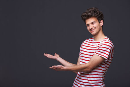 Smiling handsome man showing open hand palm with copy space for product or textの写真素材