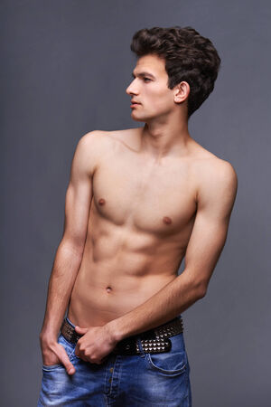 Male fashion model with modern haircut posing shirtless over dark backgroundの写真素材