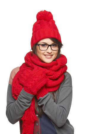 Winter, christmas, holidays concept. Smiling beautiful woman in glasses and in red hat, scarf and mittens over white backgroundの写真素材