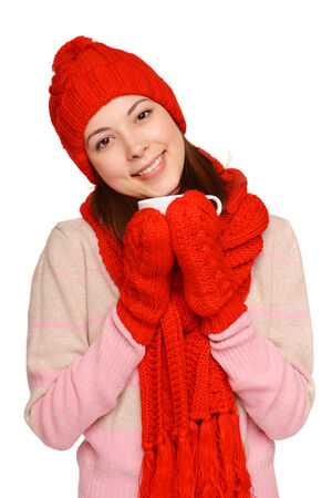 Beautiful woman with red knitted scarf, gloves and hat holding white cupの写真素材