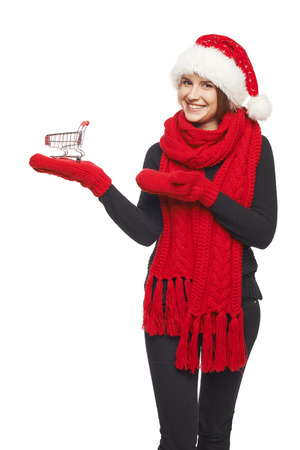 Smiling beautiful woman in Santa hat, scarf and mittens showing open hand palm with copy space for product or textの写真素材