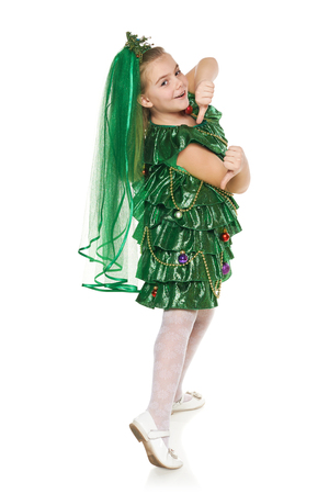 Funny 7 years old girl in Christmas tree costume feeling happy gesturing thumbs up, over white backgroundの写真素材