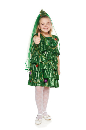 Happy 7 years old girl in Christmas tree costume giving you thumb up, over white backgroundの写真素材