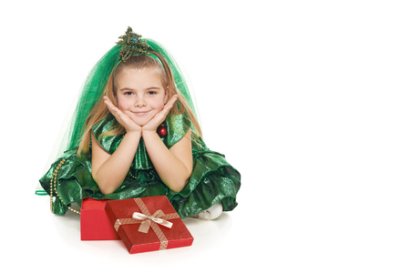 Little girl in Christmas tree costume sitting on the floor with opened red gift box, over white backgroundの写真素材