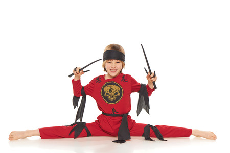Young Ninja doing the splits and holding sabres over white backgroundの写真素材