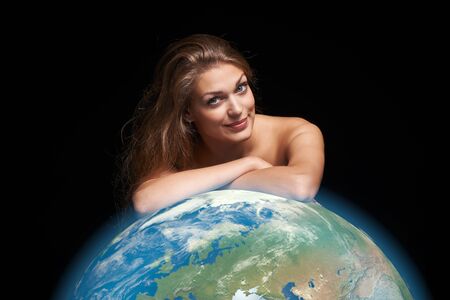 Environmental, eco concept. Closeup portrait of young female leaning on 3D rendered Earth globe over black backgroundの写真素材