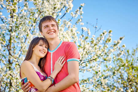 Young couple enjoying in blooming garden looking away