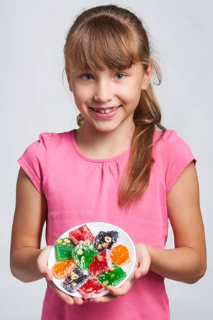 Happy little girl holding a plate with colorful jelly candies sweets Turkish delightsの写真素材