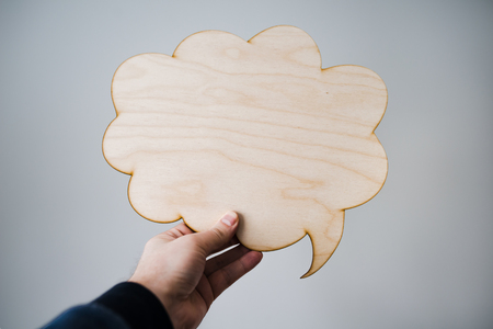 Male hand holding blank wooden thoughts cloudの写真素材