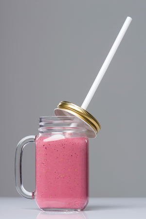 Jar tumbler mug with pink smoothie drink on tableの写真素材