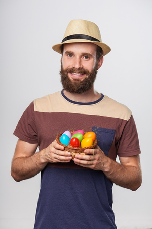 Bearded hipster man holding a basket with Easter eggsの写真素材