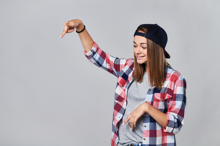 Teen girl pointing to the side down at empty copy space, over grey backgroundの写真素材
