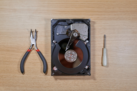 Disassembled hard disk drive lying on table with different repair tools