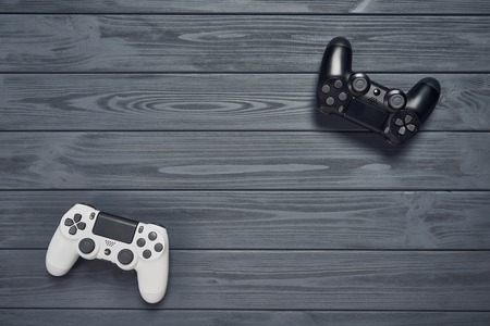 Computer game competition. Gaming concept. Top view of two joysticks on wooden table with copy spaceの写真素材