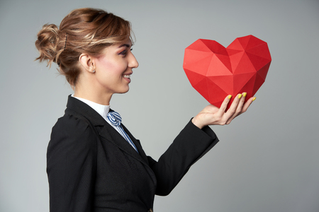 Side view of business woman holding red polygonal paper heart shapeの写真素材