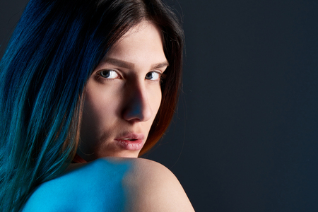 Closeup of young woman on dark background with blue backlitの写真素材