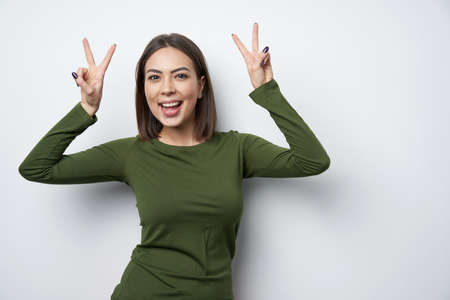 Happy woman gesturing peace sign looking at camera smilingの写真素材