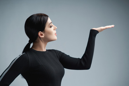 Profile portrait of a woman holding blank copy space on her palm, over gray backgroundの写真素材