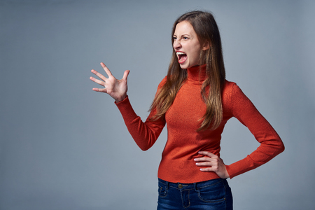 Angry woman screaming over gray backgroundの写真素材