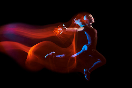 Fine art portrait of young sport woman running, with a light train behind her. Mixed lighting photography.の写真素材
