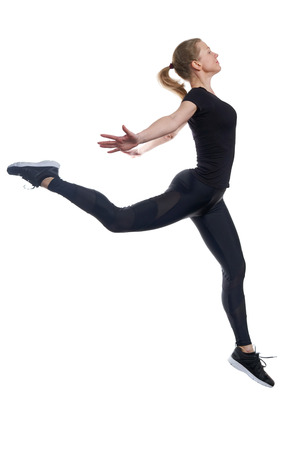 Side view of sportive active girl in motion jumping in the air on white studio backgroundの写真素材